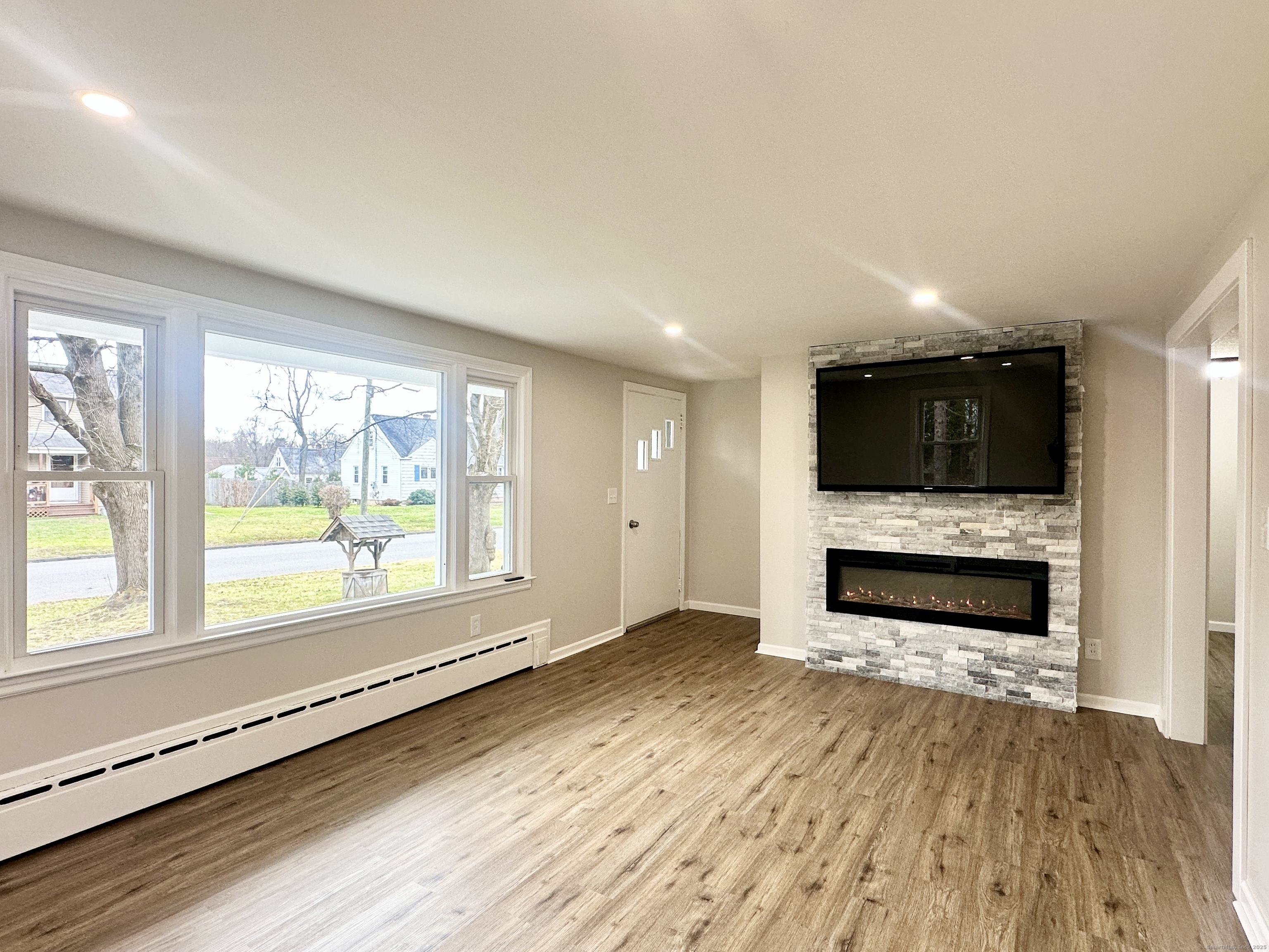 9 Eleanor Road Enfield, CT 06082 - Photo 14 of 32 an empty room with wooden floor a fireplace and windows