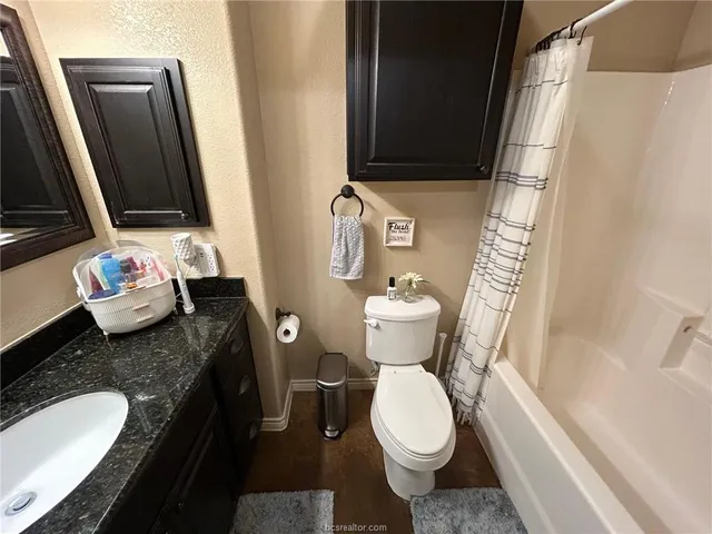 a bathroom with a granite countertop toilet sink and mirror