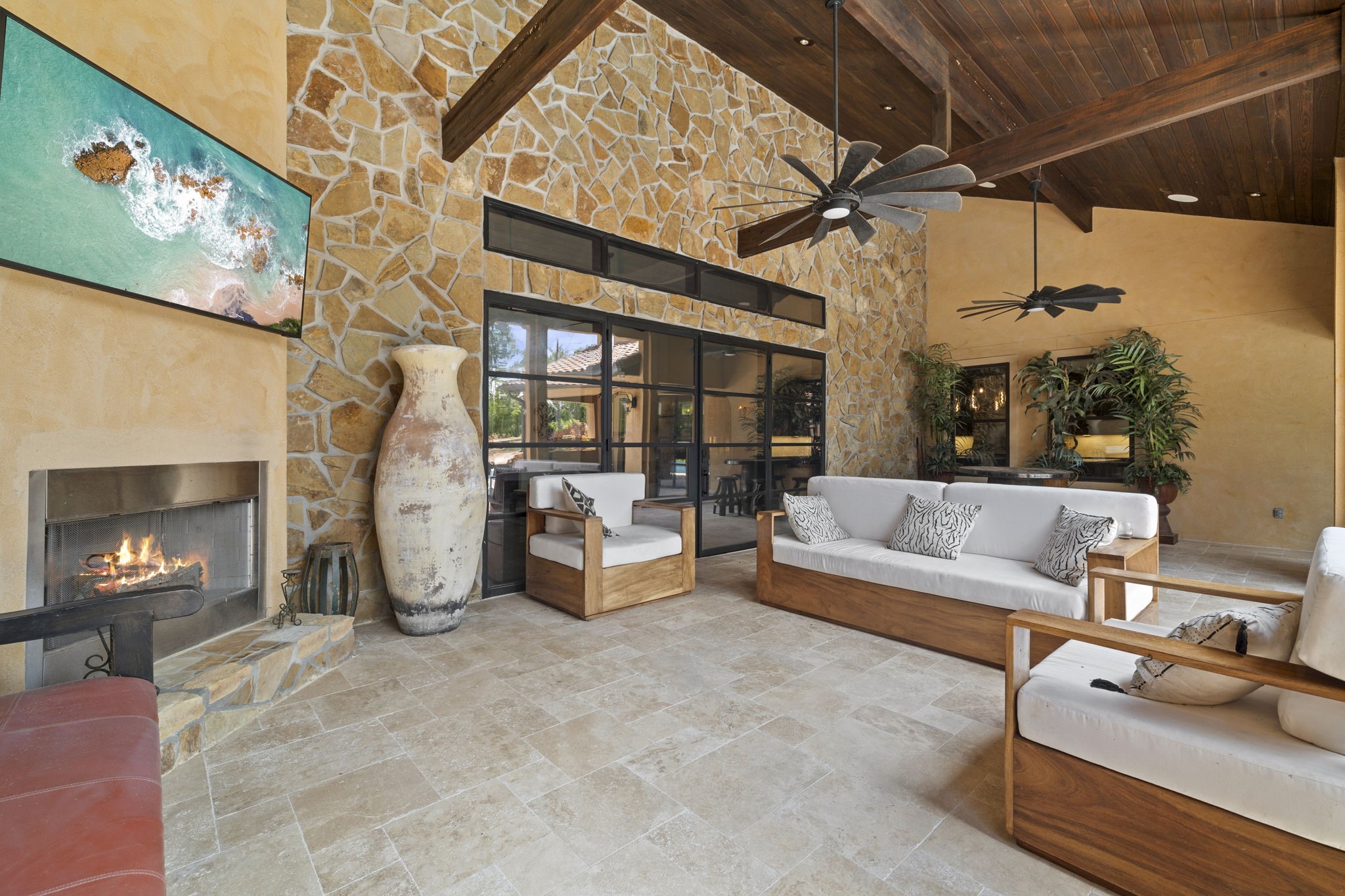 4322 Maple Rapids Court Spring, TX 77386 - Photo 4 of 48 Patio with stone wall, gas outdoor fireplace, wood vaulted ceilings, travertine tile, double iron doors leading into living room.