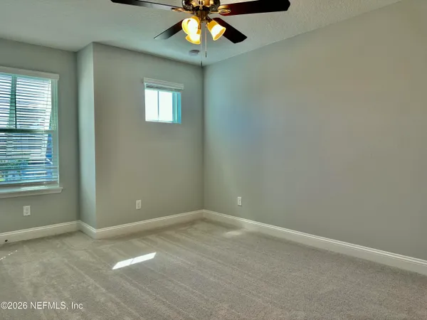 an empty room with windows and fan