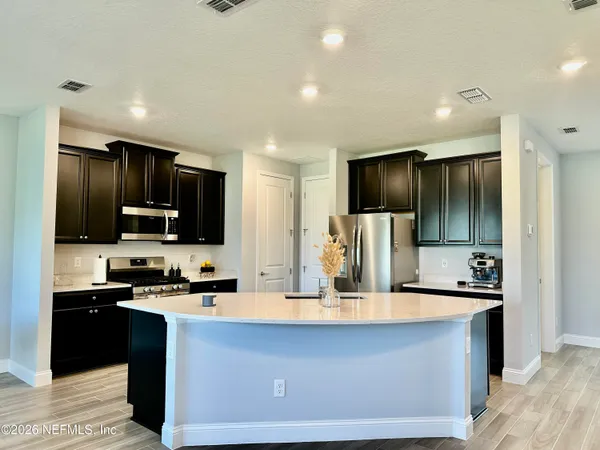 a kitchen with kitchen island granite countertop stainless steel appliances a sink stove refrigerator and cabinets