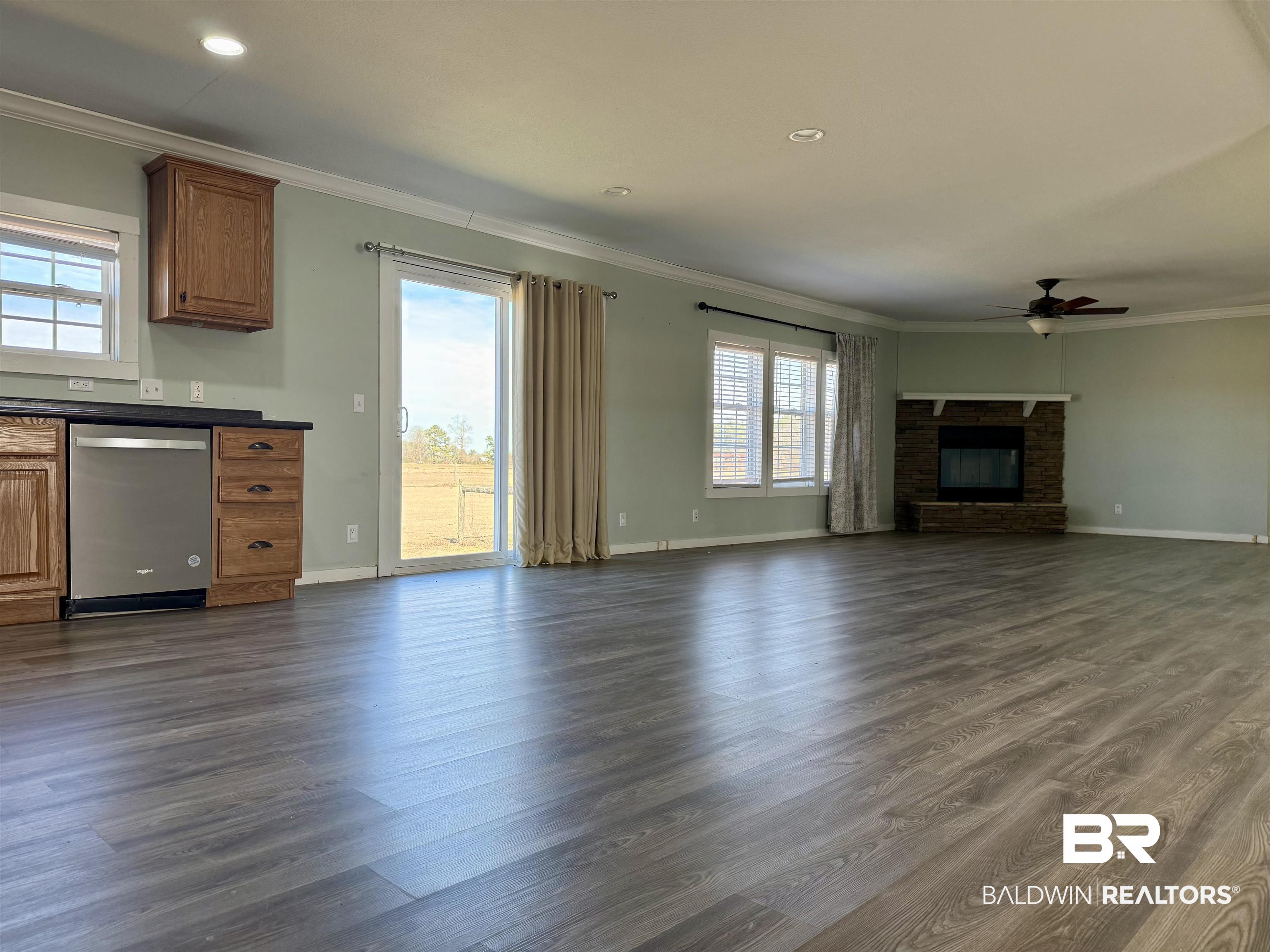 1064 Old Fannie Road Flomaton, AL 36441 - Photo 5 of 17 Unfurnished living room featuring crown molding, healthy amount of natural light, a brick fireplace, dark wood finished floors, and recessed lighting