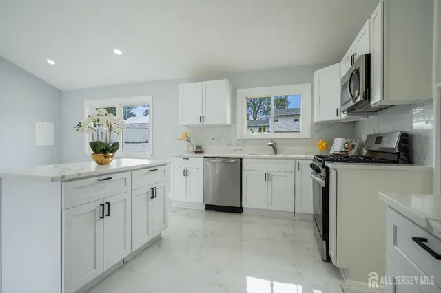 a kitchen with stainless steel appliances a refrigerator sink stove and white cabinets