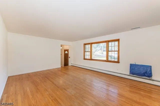 a view of an empty room with a window and wooden floor