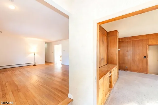 a view of a hallway with wooden floor and a bathroom
