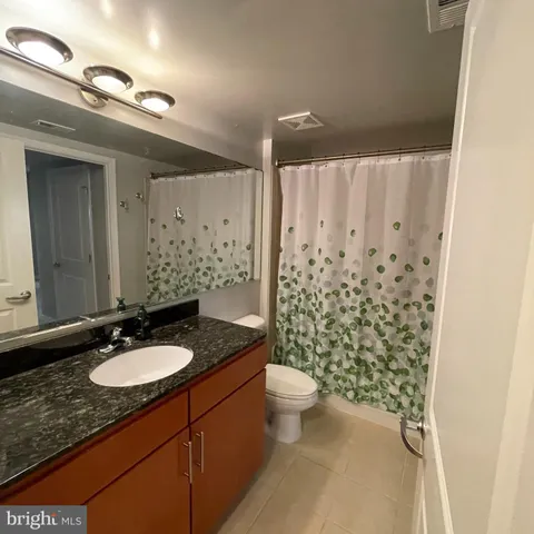 a bathroom with a granite countertop sink toilet a mirror and shower