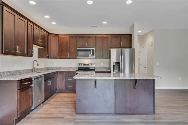 a large kitchen with wooden floors stainless steel appliances a sink and cabinets