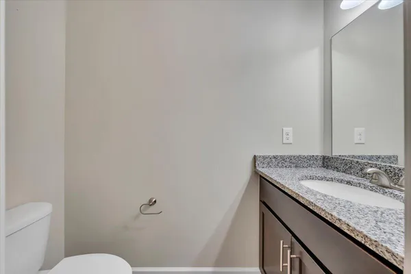 a bathroom with a granite countertop sink and a toilet