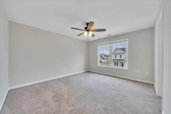 an empty room with windows and fan