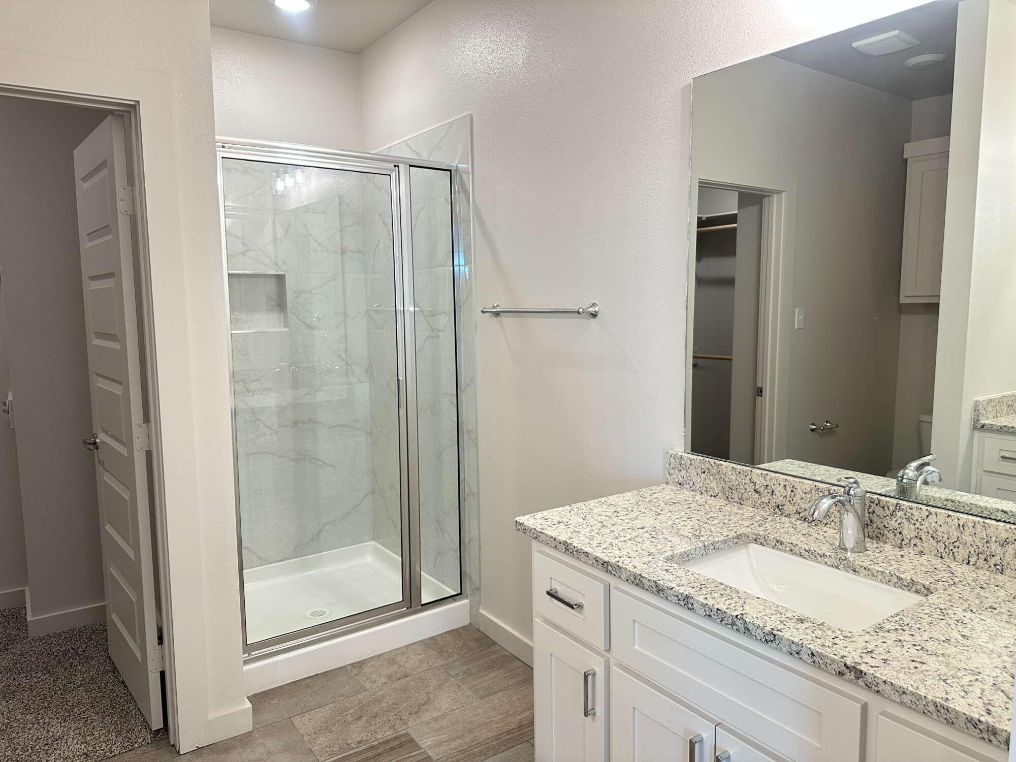 1113 North 7th Street Wolfforth, TX 79382 - Photo 10 of 17 a bathroom with a granite countertop sink a mirror and shower