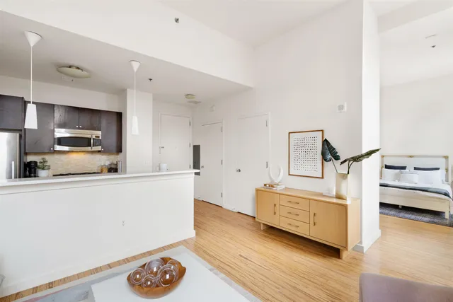 a living room with stainless steel appliances furniture and a wooden floor