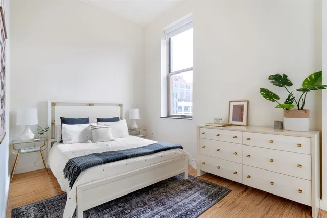 a bedroom with a bed potted plant on the dresser and a window