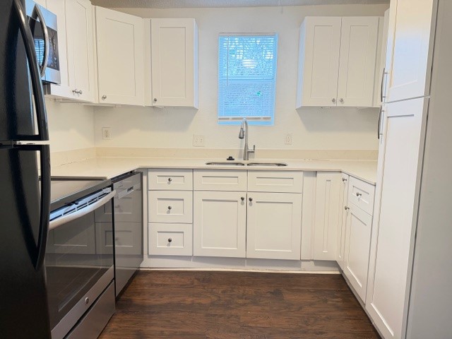 2910 East 12th Street Austin, TX 78702 - Photo 1 of 18 Kitchen with appliances with stainless steel finishes, white cabinetry, dark wood finished floors, and light stone counters