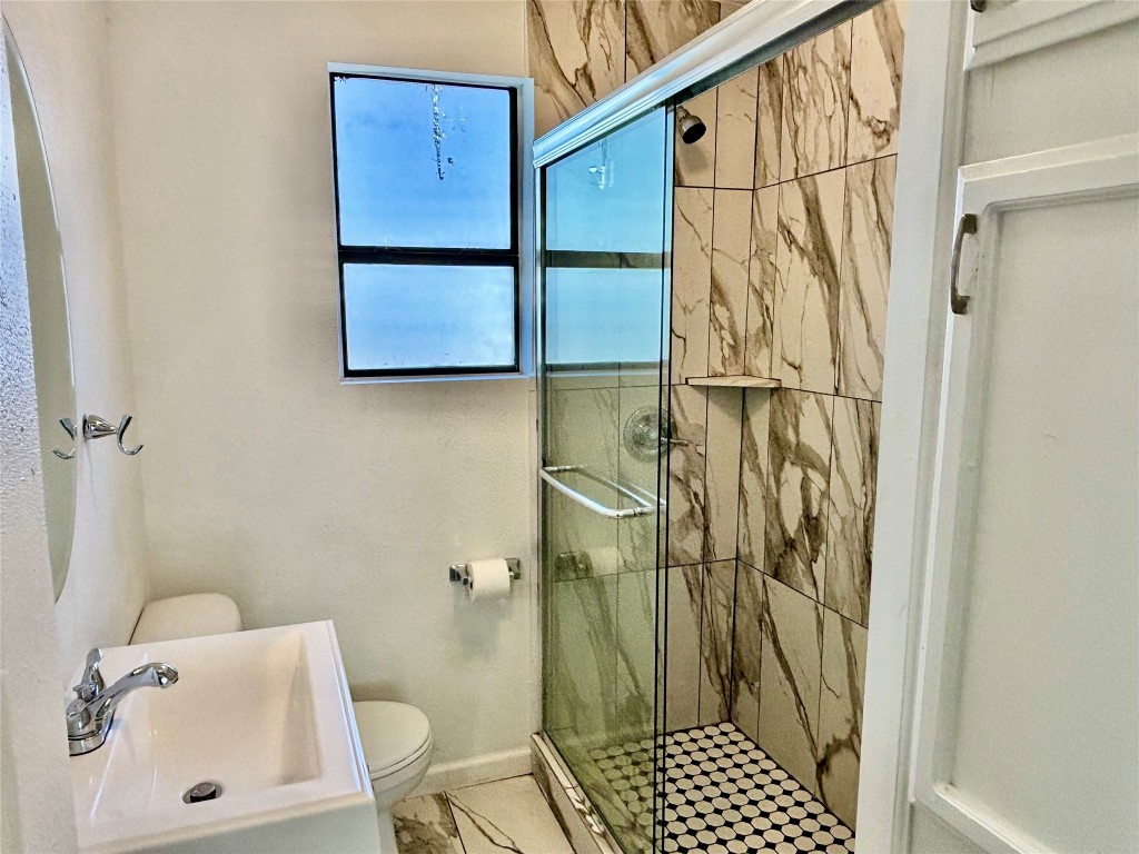 2910 East 12th Street Austin, TX 78702 - Photo 13 of 18 Full bath featuring a sink, toilet, a stall shower, and baseboards