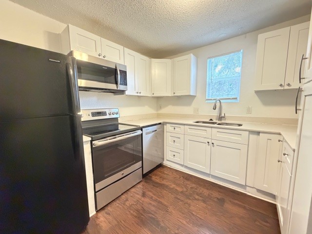 2910 East 12th Street Austin, TX 78702 - Photo 5 of 18 Kitchen with appliances with stainless steel finishes, white cabinets, a textured ceiling, and dark wood finished floors