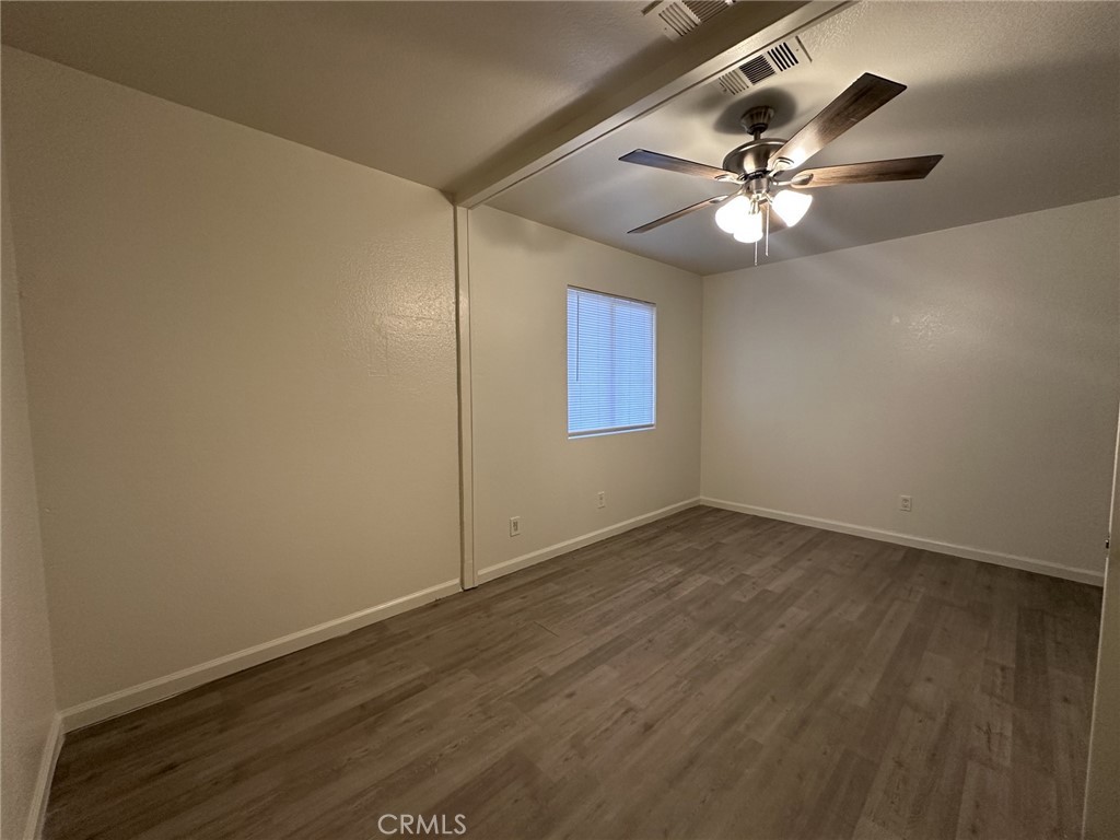 11807 Lupin Road Adelanto, CA 92301 - Photo 3 of 8 a view of an empty room with wooden floor and a ceiling fan