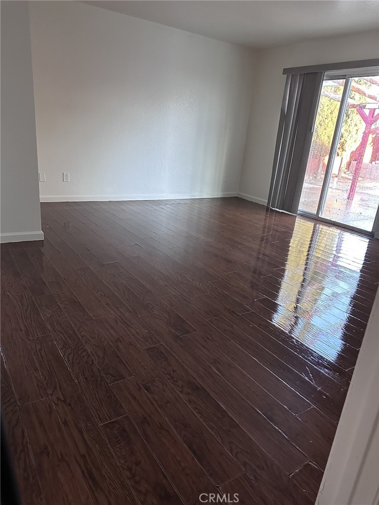 11807 Lupin Road Adelanto, CA 92301 - Photo 4 of 8 an empty room with wooden floor and windows