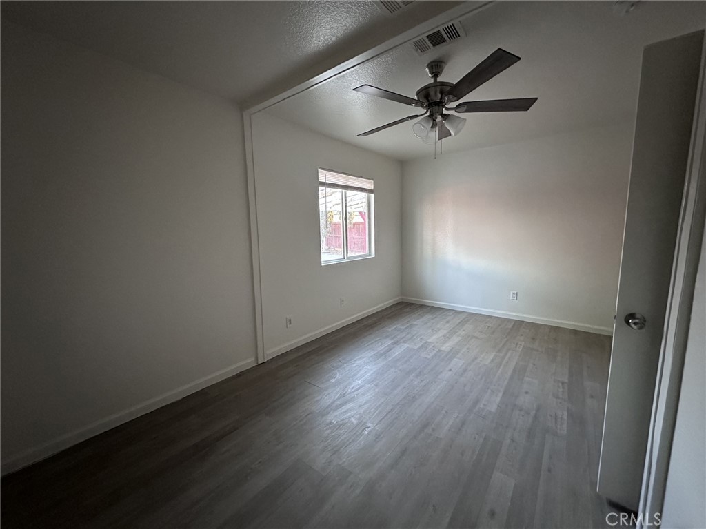 11807 Lupin Road Adelanto, CA 92301 - Photo 6 of 8 an empty room with wooden floor fan and windows