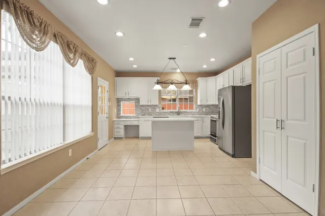 a large white kitchen with a refrigerator a sink and cabinets