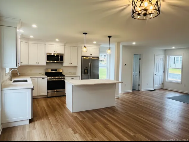 a kitchen with stainless steel appliances a stove top oven a sink cabinets and a wooden floor