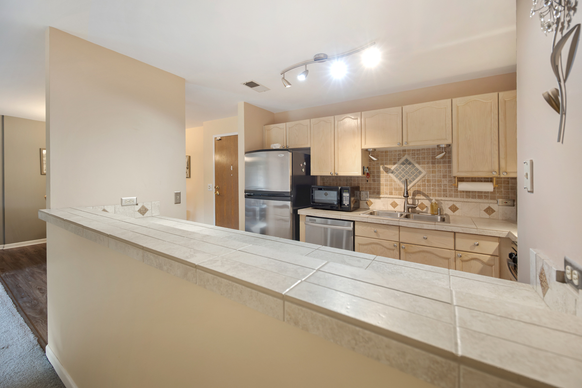815 Leicester Road, Unit 114A Elk Grove Village, IL 60007 - Photo 13 of 20 a large white kitchen with cabinets