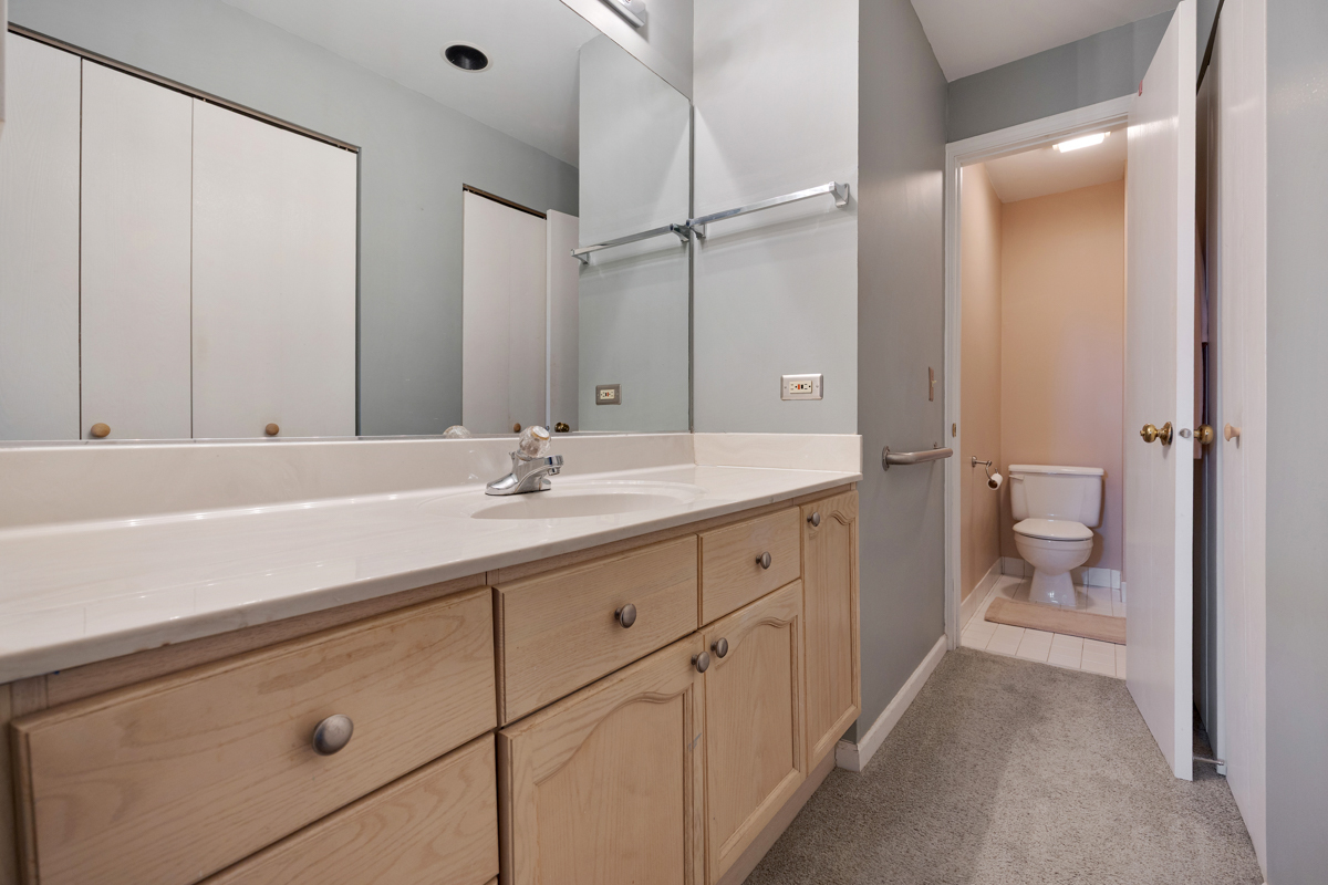 815 Leicester Road, Unit 114A Elk Grove Village, IL 60007 - Photo 16 of 20 a bathroom with a double vanity sink toilet and shower