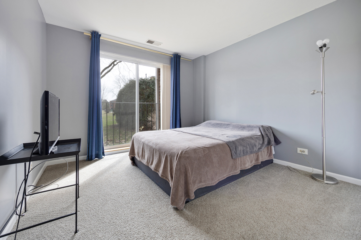 815 Leicester Road, Unit 114A Elk Grove Village, IL 60007 - Photo 18 of 20 a bedroom with a bed flat screen tv and a large window