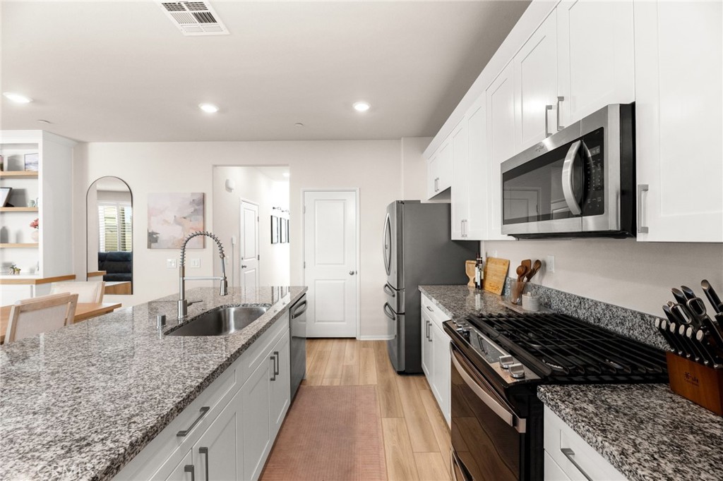 36362 Arcs Street Winchester, CA 92596 - Photo 17 of 54 a kitchen with granite countertop stainless steel appliances a stove a sink a refrigerator microwave and cabinets