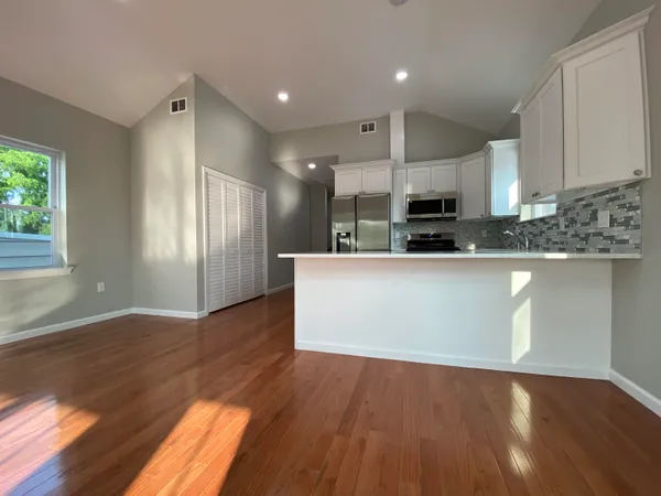 a large kitchen with kitchen island a sink wooden floor and view living room