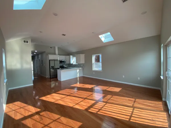 a view of hallway with window and wooden floor