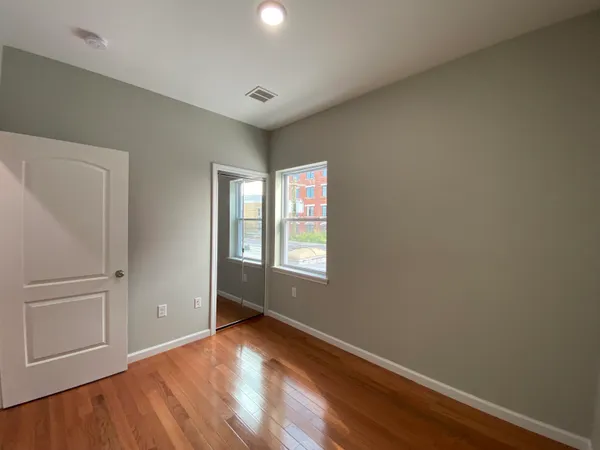 an empty room with wooden floor and windows