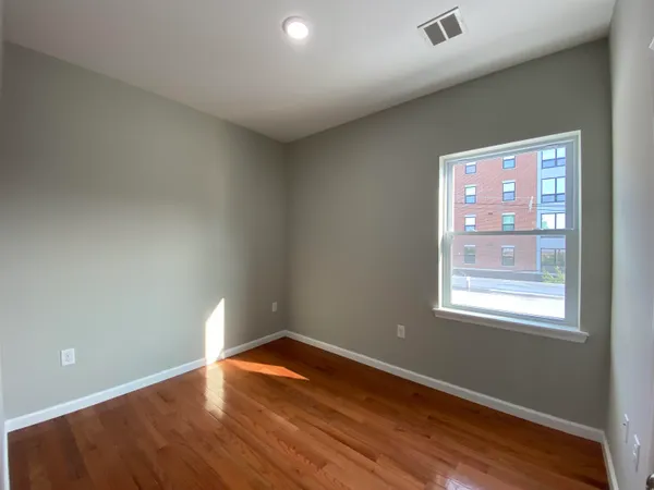 an empty room with wooden floor and windows