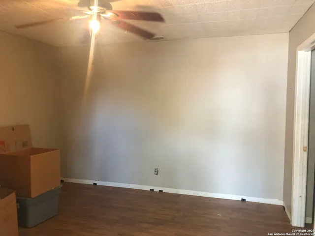 an empty room with a ceiling fan and wooden floor