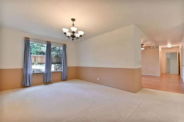 a view of an empty room with a chandelier fan