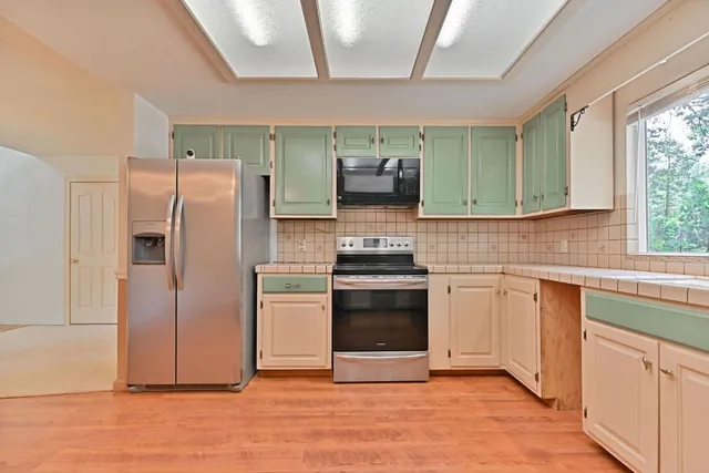 a view of an empty room with wooden floor and windows