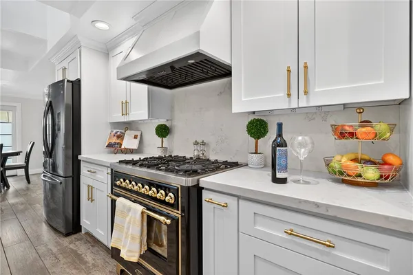 a kitchen with stainless steel appliances granite countertop a stove a refrigerator and a white cabinets