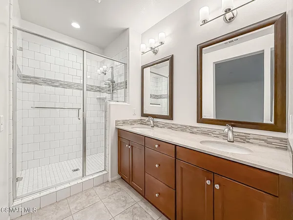 a bathroom with a double vanity sink mirror and shower