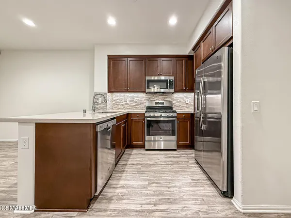 a kitchen with stainless steel appliances granite countertop a stove a sink and a refrigerator