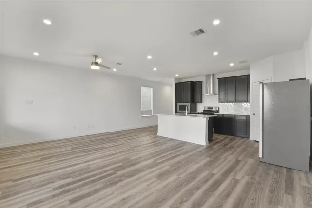 a large kitchen with stainless steel appliances a large counter top a stove and a refrigerator