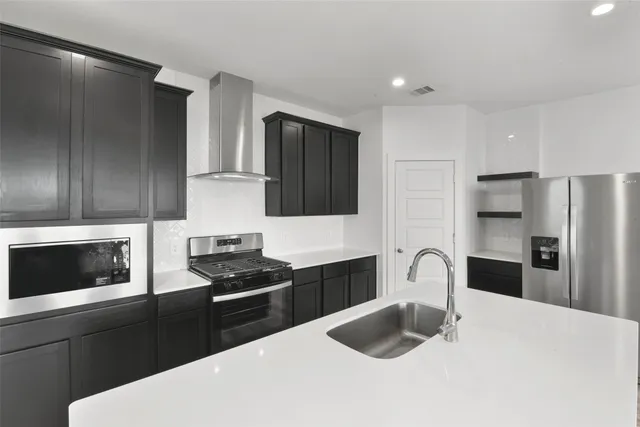 a kitchen with granite countertop a refrigerator stove and sink