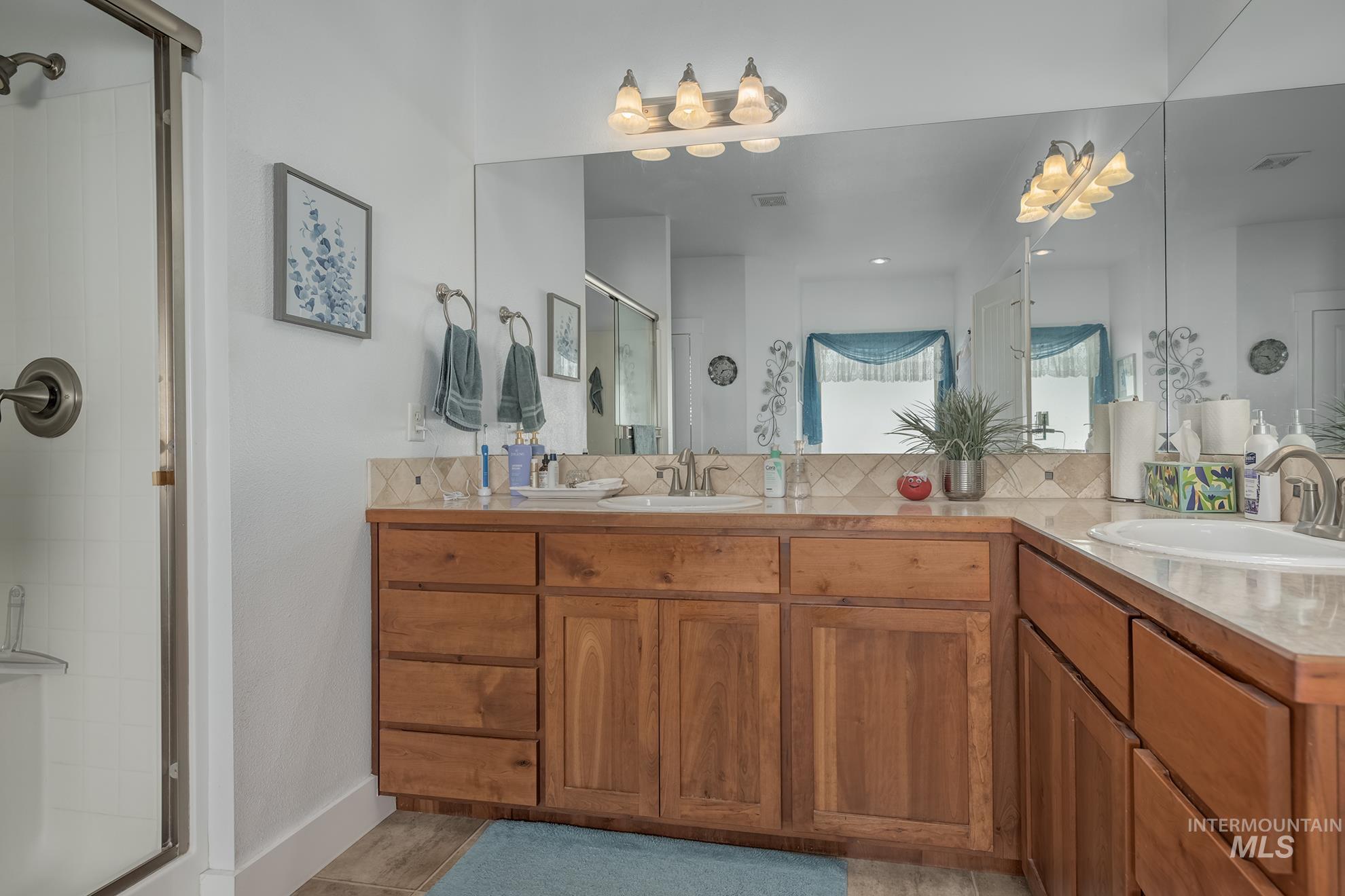 420 West Indianhead Road Weiser, ID 83672 - Photo 24 of 40 Bathroom featuring a wood-finish vanity with multiple drawers, dual integrated sinks, and a full-width mirror