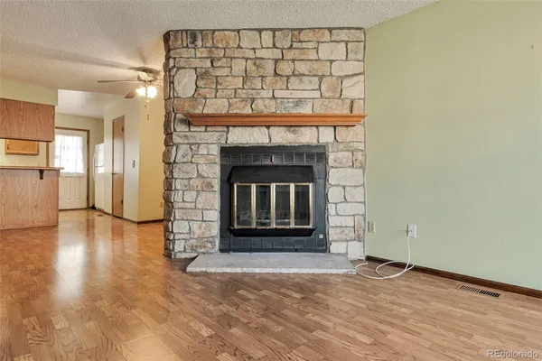 an empty room with wooden floor a fireplace and windows