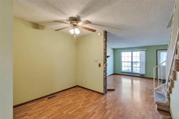 an empty room with wooden floor fan and windows