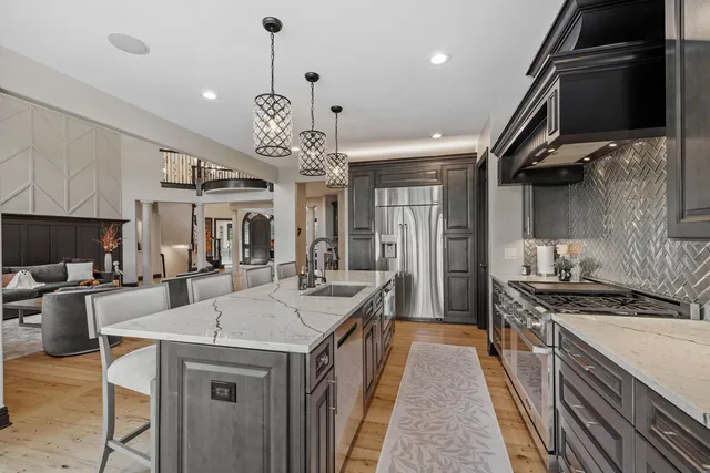 a kitchen with a stove a sink a kitchen island with chairs and wooden floor