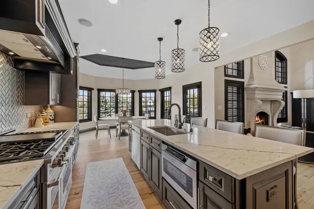 a large kitchen with stainless steel appliances granite countertop a stove a sink dishwasher a dining table and chairs with wooden floor