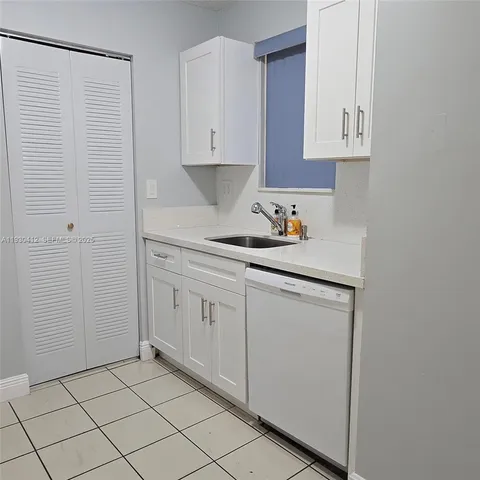 a kitchen with white cabinets and sink