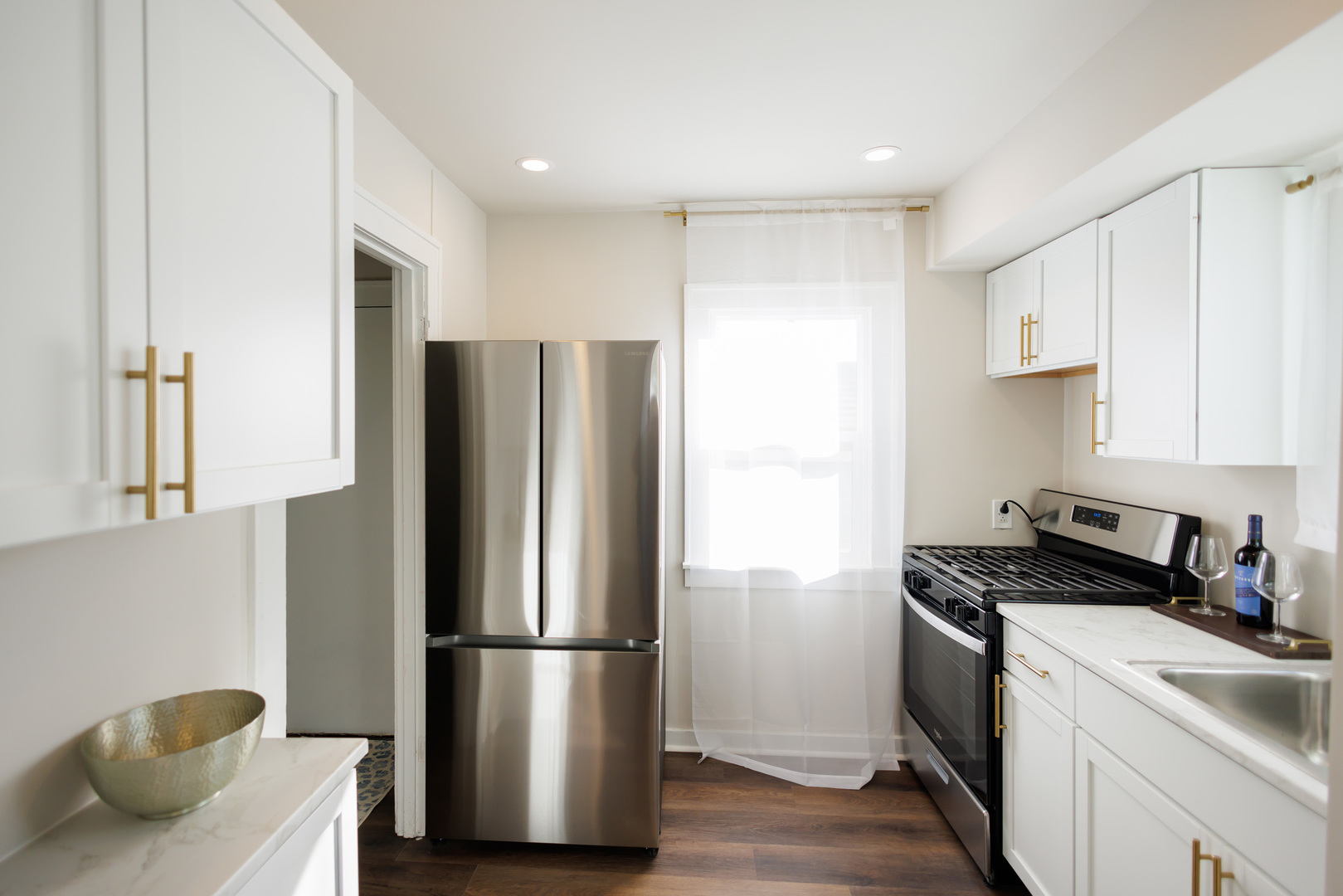 1240 West Merchant Street Kankakee, IL 60901 - Photo 9 of 25 a kitchen with stainless steel appliances a refrigerator a sink a stove and white cabinets