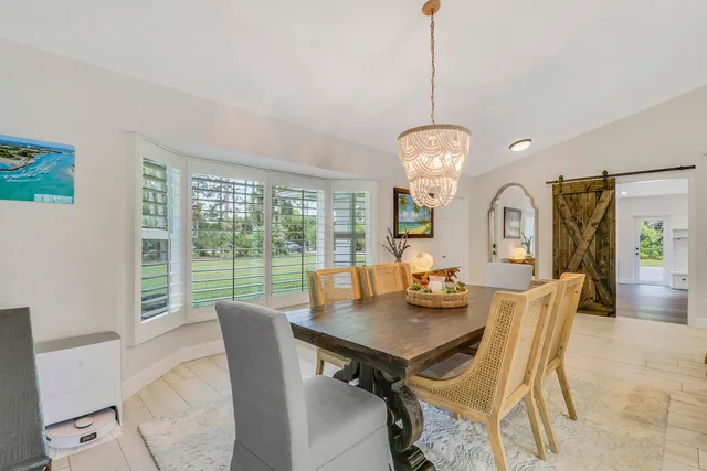 a dining room with wooden floor a chandelier a wooden table and chairs