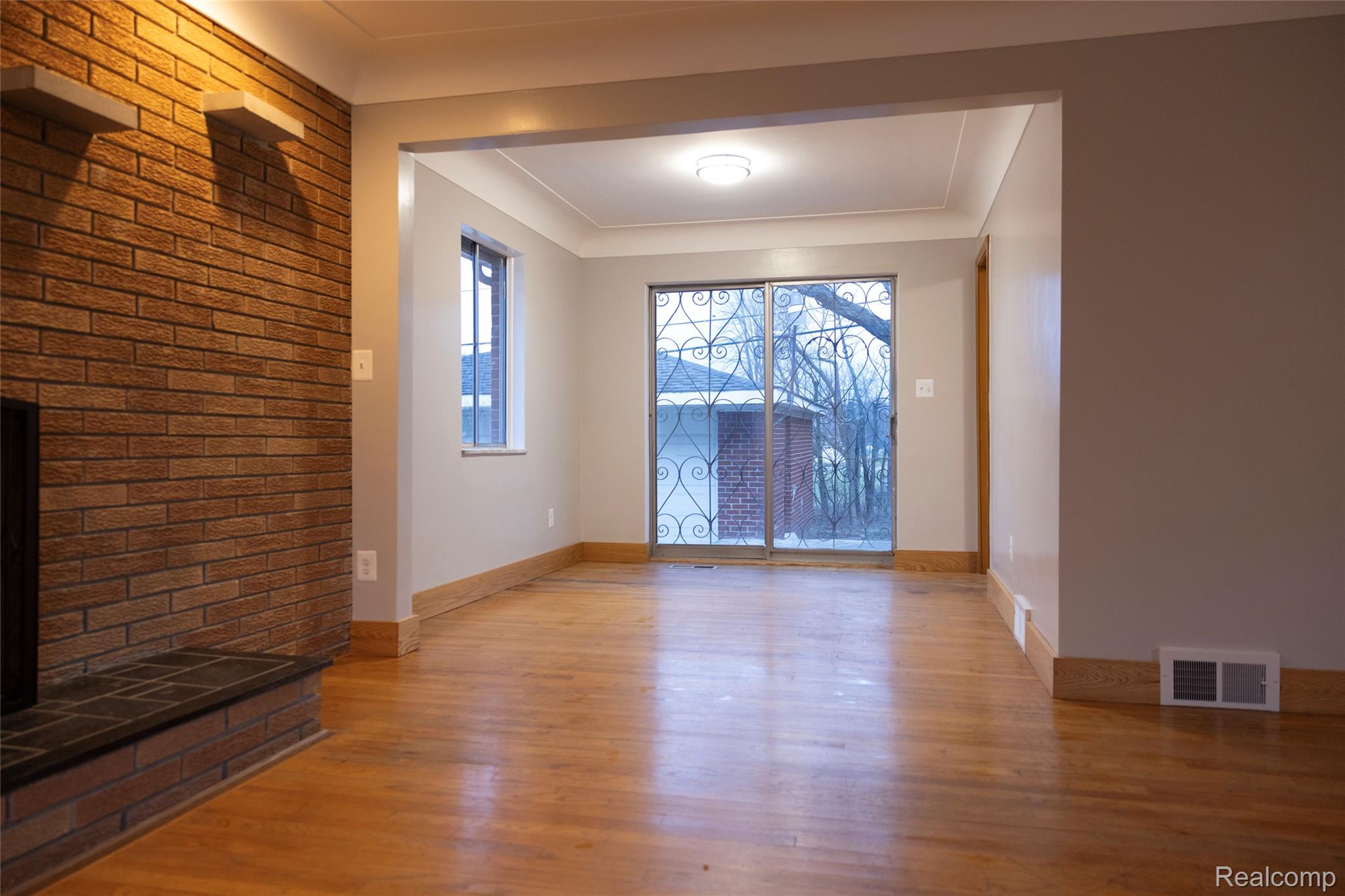 4191 Allen Avenue Inkster, MI 48141 - Photo 6 of 13 Unfurnished living room with light wood-style flooring, a fireplace with raised hearth, and brick wall