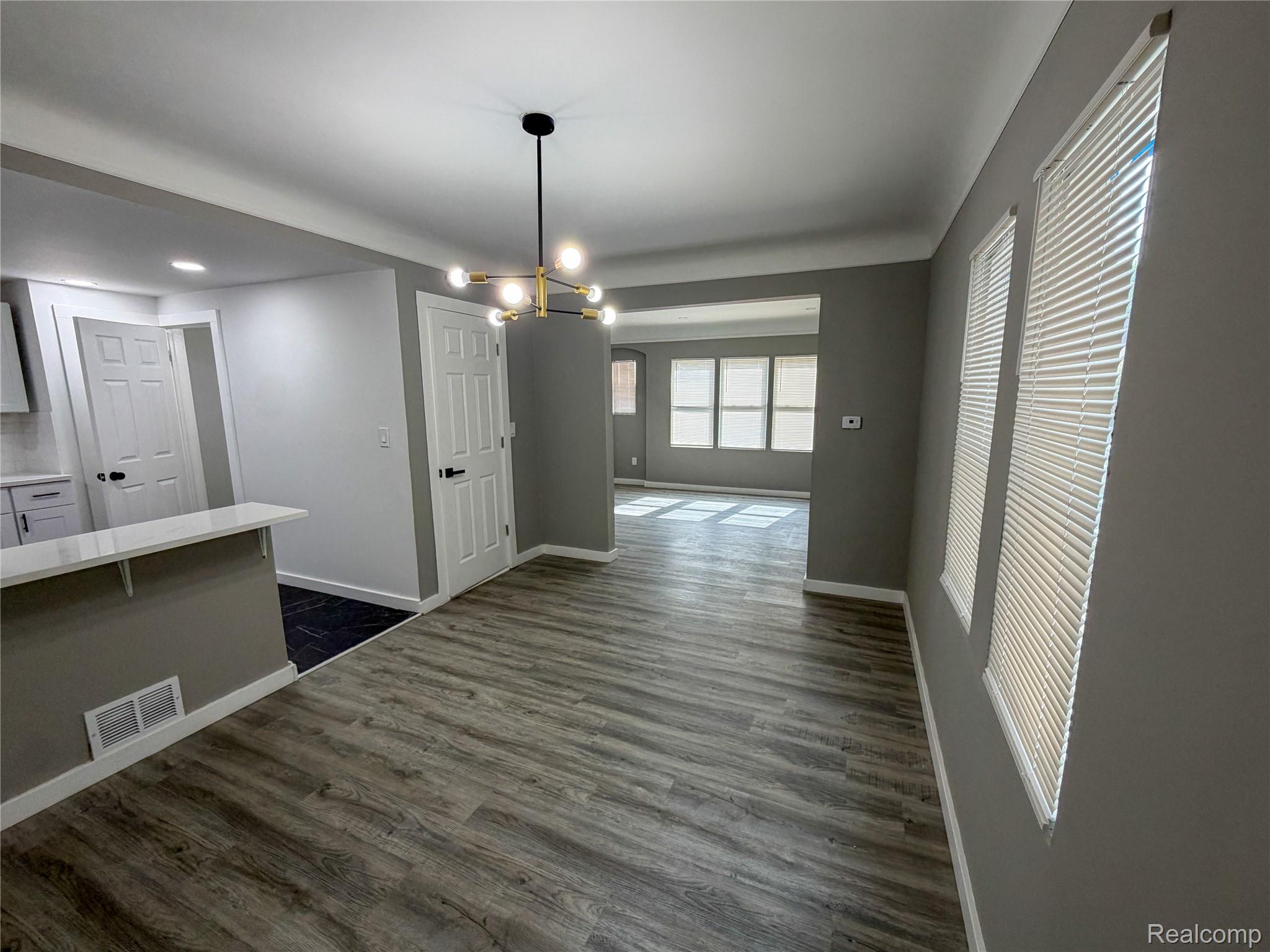 18217 Prairie Street Detroit, MI 48221 - Photo 8 of 34 Dining area featuring wood-finish flooring, a contemporary chandelier, two windows with blinds, and painted walls